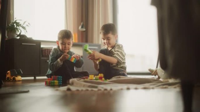 白天，两个亚洲男性孩子在房间里玩五颜六色的积木的肖像。老大哥帮助弟弟建造玩具屋。童年和纯真的概念