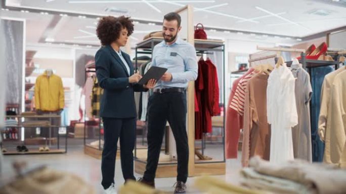 服装店: 女商人使用平板电脑，与视觉商品专家交谈，合作创建时尚的系列。小型企业时装店销售经理与设计师