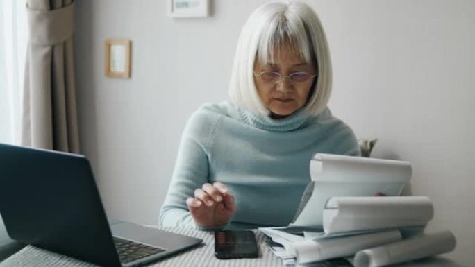 老年妇女在笔记本电脑上支付账单或做家庭财务