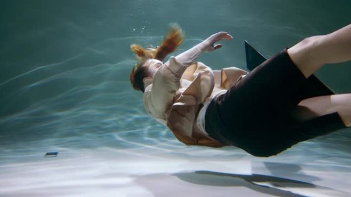 年轻女商人的电影视角沉入水中，智能手机慢动作。压力和抑郁概念