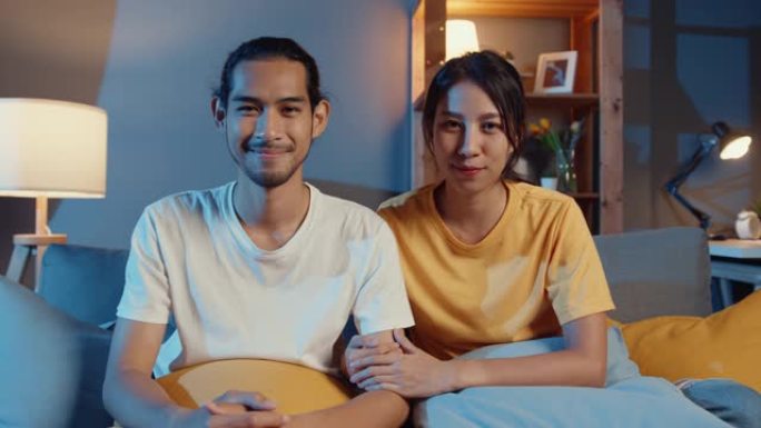 幸福的年轻亚洲夫妇晚上在家里的客厅在线视频通话中看着相机微笑和快乐。