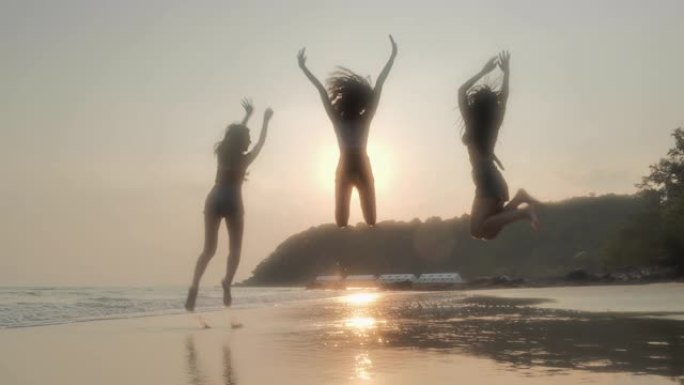 剪影三个十几岁的女孩在夏天，友谊，海上，暑假，假期和人们的概念，假期一起在海滩上跳跃。东南亚和东亚: