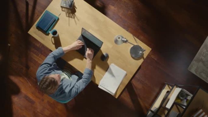 顶视图静态拍摄家庭办公室: 坐在办公桌前的自由企业家在笔记本电脑上工作。专业在家工作，远程访问公司员