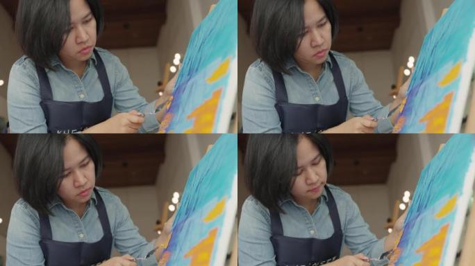 成人中年亚洲妇女在学校咖啡馆绘画艺术产品。