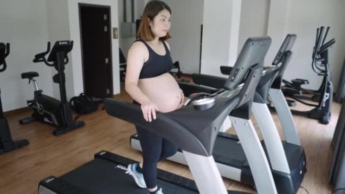 孕妇在健身室锻炼，在跑步机上行走，身体健康和有氧运动