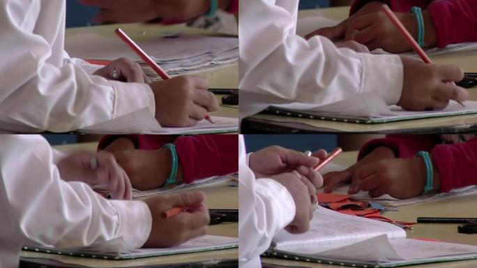 在阿根廷公立学校上课时，小学生在素描时使用橙色铅笔。特写。