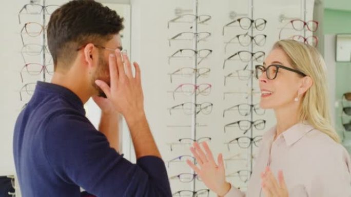 配镜师帮助客户在验光时选择眼镜。男性顾客咨询验光师配戴眼镜的眼镜，以提高视力并检查镜子