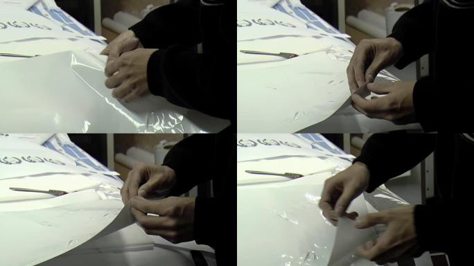 工人的手从旗厂印刷工艺部的胶膜上拉出来。特写。