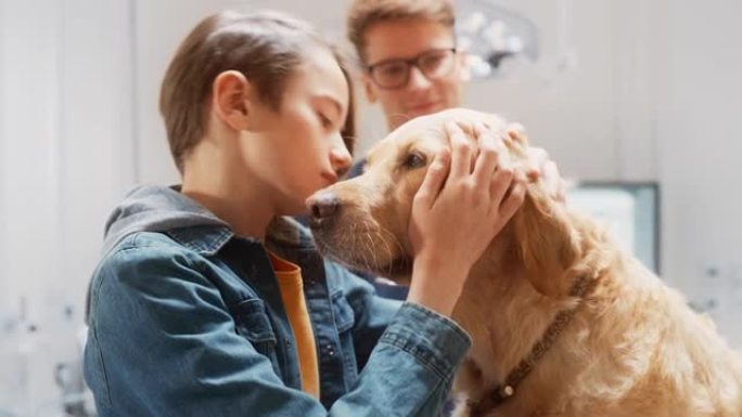 年轻的狗主人很高兴看到他的宠物金毛猎犬在现代兽医诊所接受了专业兽医的医疗程序后还活着。男孩抚摸和与狗