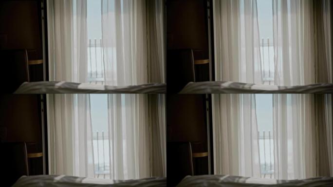 酒店房间的白色透明窗帘在风中移动，门打开，背景为大海