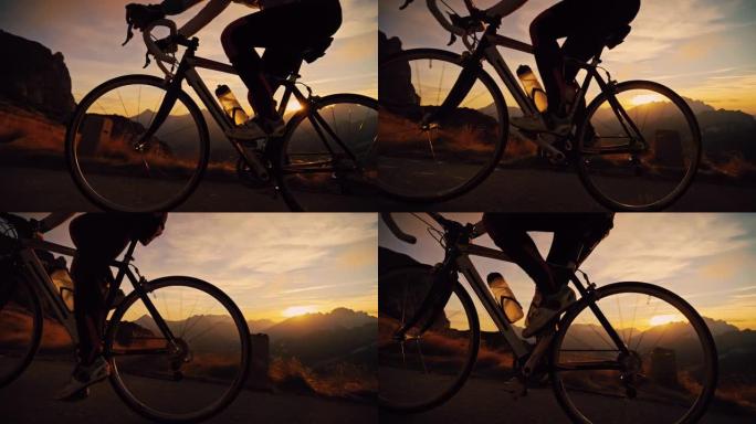 剪影的自行车手在日出山上的道路上坡骑行