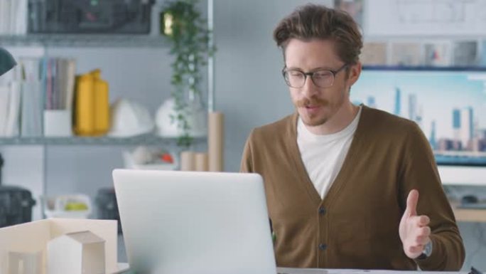 办公室的男建筑师在笔记本电脑上的办公桌上进行视频通话