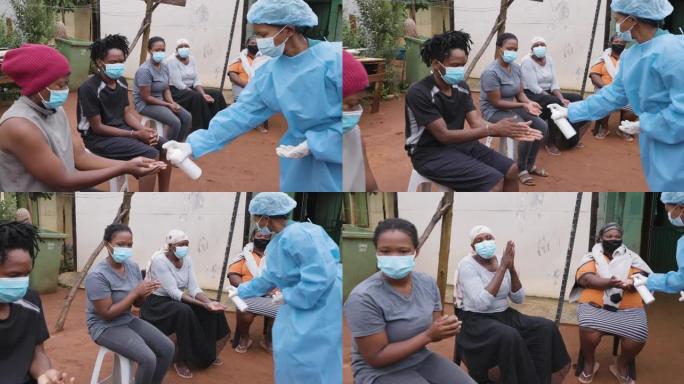 非洲黑人在农村居民点排队接种新冠疫苗。护士在手上喷洒消毒剂