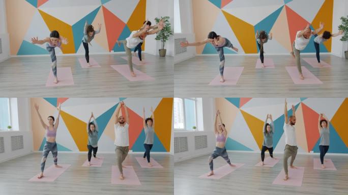 在瑜伽馆锻炼的年轻人的慢动作在垫子上做平衡体式