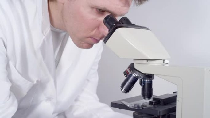特写: 专注的医生通过显微镜观察冠状病毒的应变。