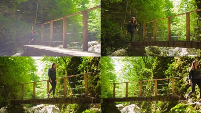 年轻的身体意识的女人在郁郁葱葱的树叶景观中徒步穿越山溪峡谷上的木桥