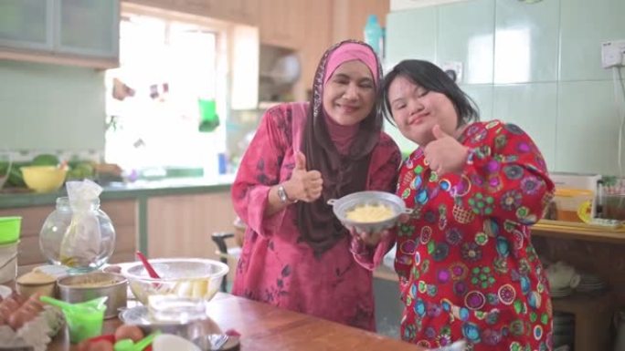 马来西亚母亲和她的唐氏综合症女儿看着相机微笑着展示自制甜点