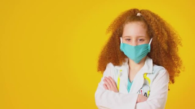 演播室拍摄的女孩打扮成医生或外科医生，戴着口罩和白色外套，听诊器在黄色背景下拍摄-慢动作拍摄