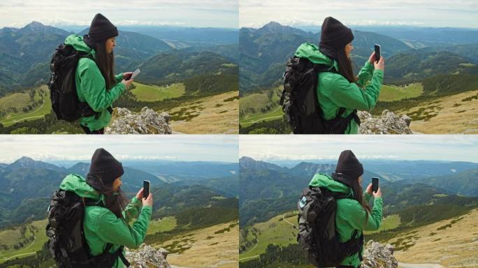 慢动作年轻背包客在山顶用智能手机拍照