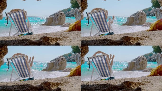 超级SLO MO女人在田园诗般的偏远海滩上海浪拍打她的沙滩椅时玩得开心