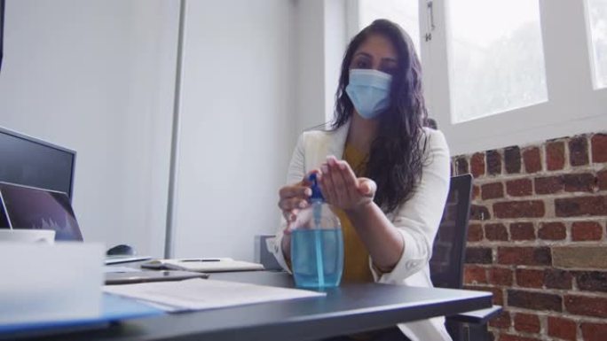 女人戴着口罩在办公室消毒双手