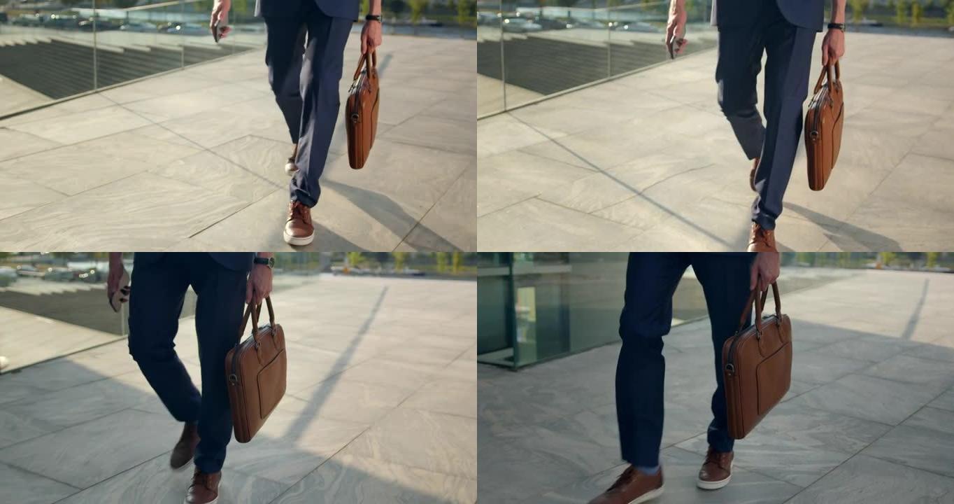 一个穿着棕色鞋子的男人的脚在铺好的街道上行走的视频，前视图