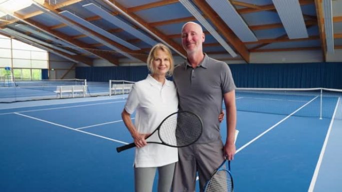 在室内网球场上站在一起的成熟夫妇