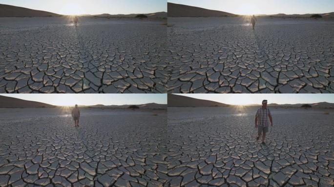 气候变化。由于气候变化和全球变暖造成的干旱，满目疮痍的农民走过干旱大坝的开裂泥面