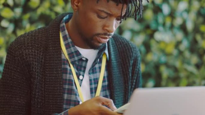 黑人，创意设计和电话，用于数字营销，广告或社交媒体，办公室配有笔记本电脑。非裔美国男性通过计算机发短