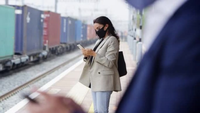 大流行期间戴着PPE口罩的铁路站台上的商务通勤者