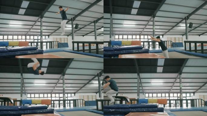 体操男子和蹦床空气跳跃与强大的能量翻转特技，用于健身房的健身训练。活跃的运动员男性在体育馆进行健康，