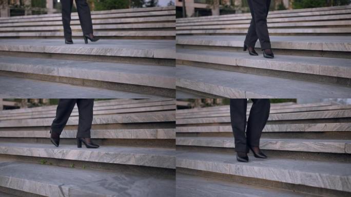 在商业区，穿着高跟鞋和经典裤子的女性脚从楼梯上走下来的特写镜头