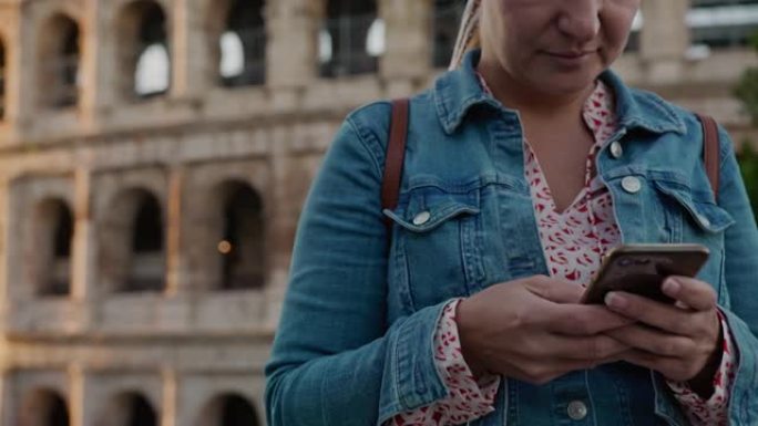 SLO MO女游客在罗马罗马斗兽场前在智能手机上打字