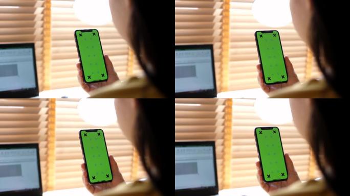 女性手中的绿屏模板智能手机在家里的镜头