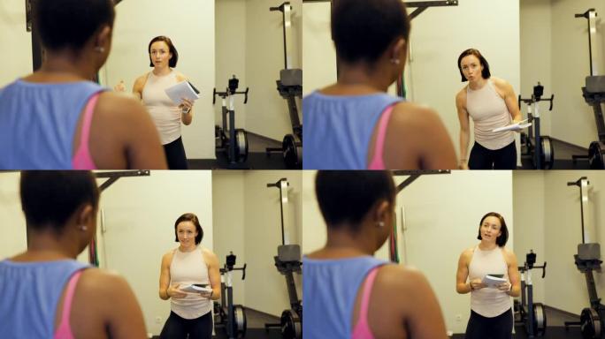 健身教练与健身房中的女性讨论锻炼计划