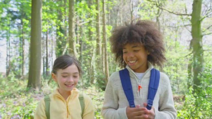 男孩和女孩穿过春季林地的风信子，朝着慢动作拍摄的镜头前视图