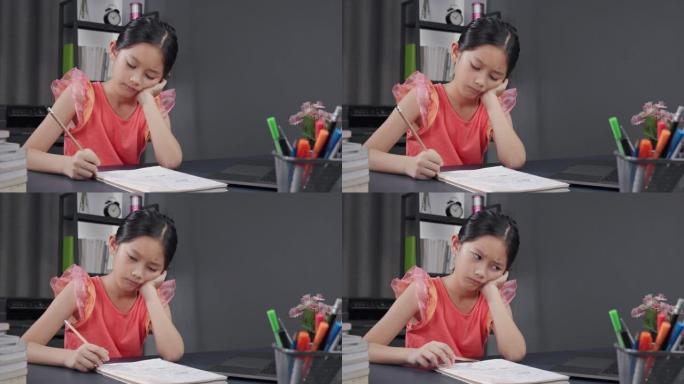 亚洲小女孩在家学习科学和在书上写笔记。家庭学校，电子学习。她在家上学的作业上使用铅笔书写。