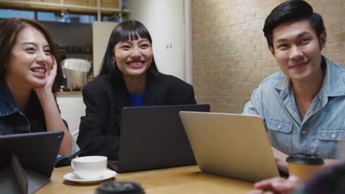一群快乐的年轻亚洲商业同事在咖啡馆餐厅的团队休闲会议启动项目讨论中使用笔记本电脑。