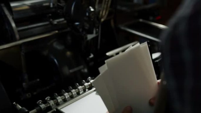 工匠造纸大师的特写镜头正在与古董墨水打印机合作，在车间生产高质量的手工纸。手工制作的概念，高品质，工