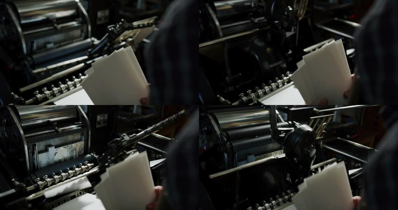 工匠造纸大师的特写镜头正在与古董墨水打印机合作，在车间生产高质量的手工纸。手工制作的概念，高品质，工