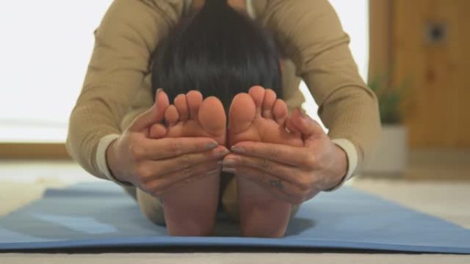 特写: 亚洲女性练习坐姿向前折叠瑜伽姿势的前视图
