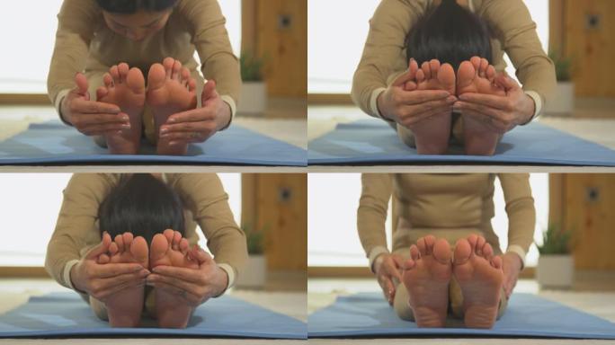 特写: 亚洲女性练习坐姿向前折叠瑜伽姿势的前视图