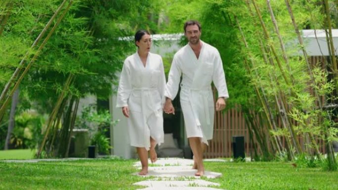 微笑的夫妇穿着浴袍走向桑拿浴室