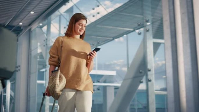 机场航站楼: 美丽的微笑女人拿着智能手机，在航空枢纽走到飞机等待她的登机口。快乐的高加索女性已经准备