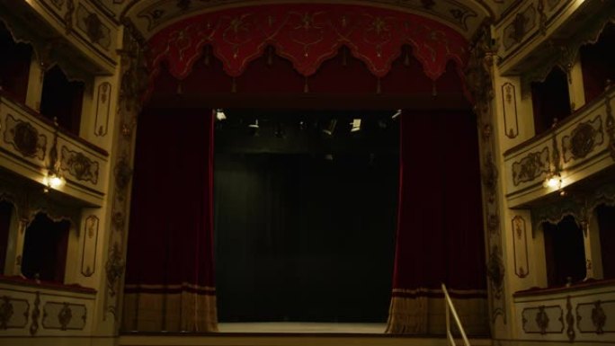 带有红色天鹅绒窗帘的空经典剧院的电影镜头打开舞台，并带有戏剧性的灯光