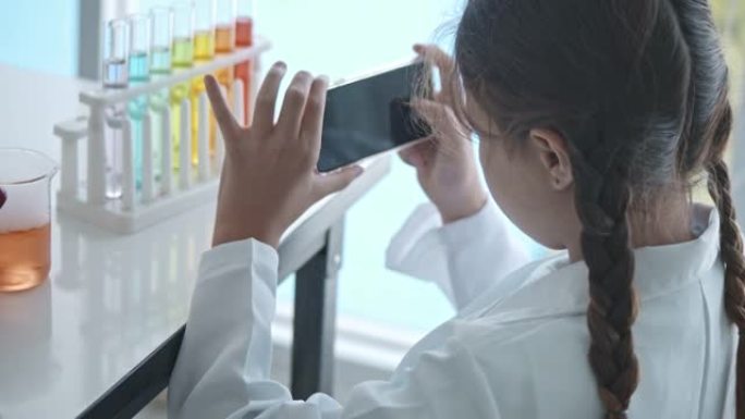 可爱的女孩使用智能手机在实验室中拍摄实验照片