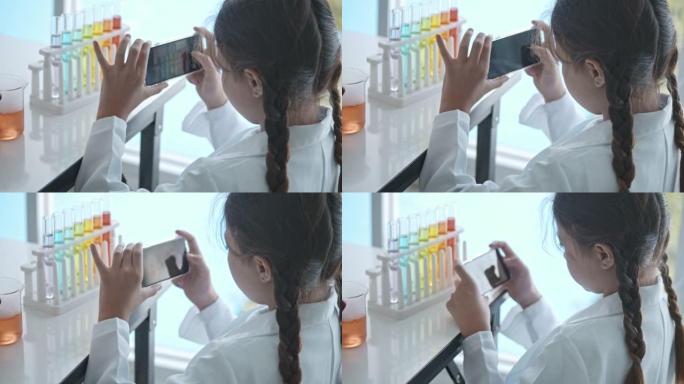 可爱的女孩使用智能手机在实验室中拍摄实验照片
