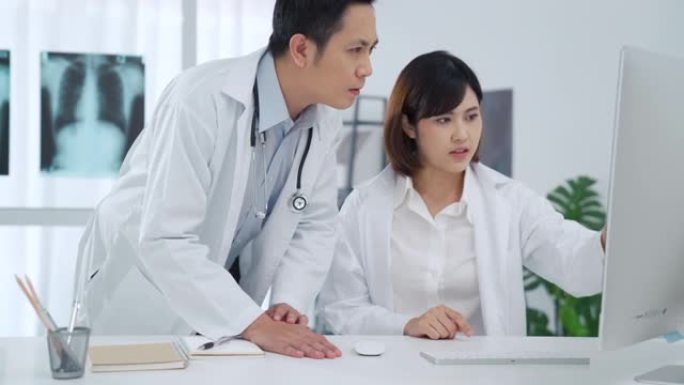 两名医生在医疗室监控计算机屏幕上进行分析和讨论