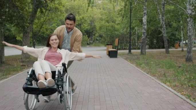 秋日坐在轮椅上的快乐男人和残疾女人在公园玩耍的慢动作