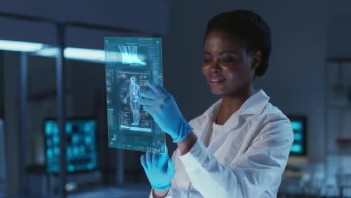 美丽的年轻非裔美国学生穿着实验服，戴着防护手套，在现代实验室的未来派平视显示器上工作。具有深蓝色配色
